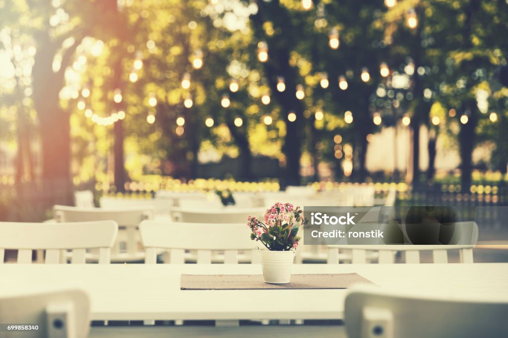 romantic outdoor restaurant in park with string lights at sunset Party - Social Event Stock Photo