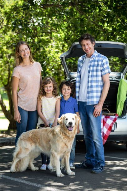 istock Smiling family standing in front of a car 699862836