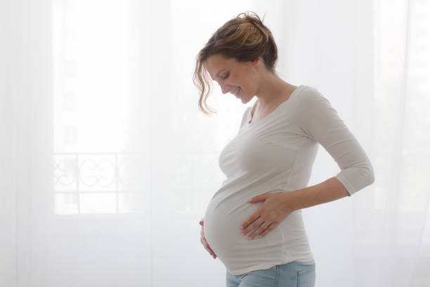 pregnant woman touching belly - holding belly fotografías e imágenes de stock