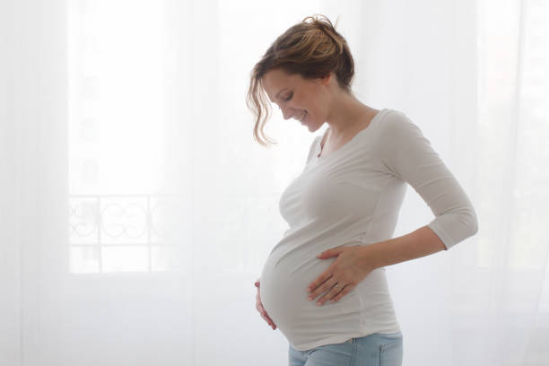 Pregnant woman touching belly stock photo