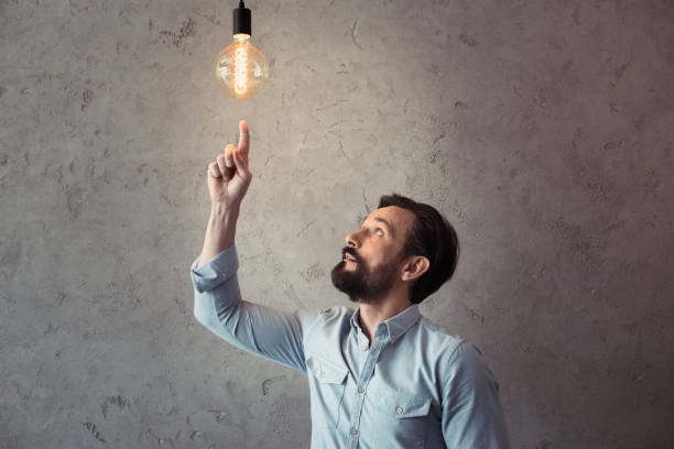 istock middle aged man pointing with finger at illuminated light bulb 699863760