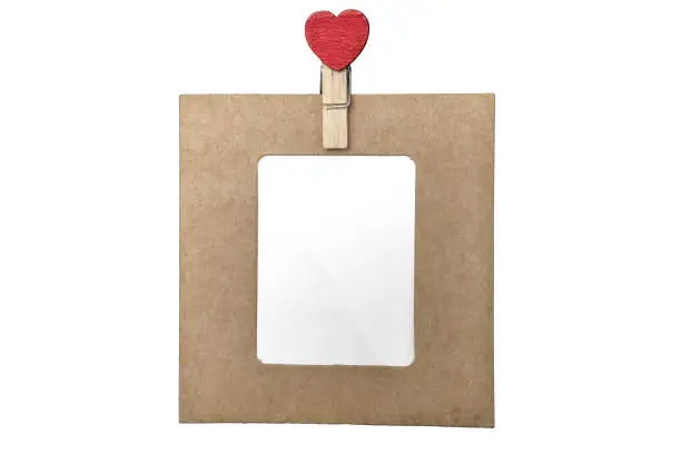 Blank frame of cardboard with a red heart clip, isolated on white background