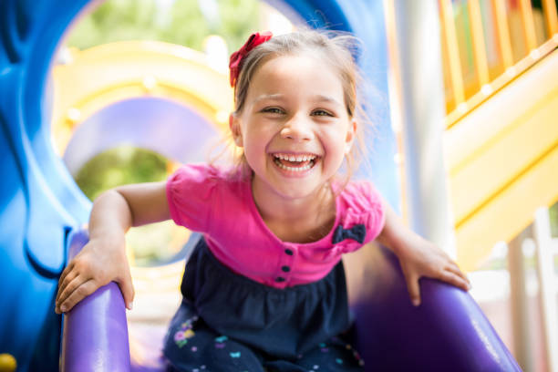 Little Girl Playing At Playground Outdoors In Summer Little Girl Playing At Playground Outdoors In Summer sliding photos stock pictures, royalty-free photos & images