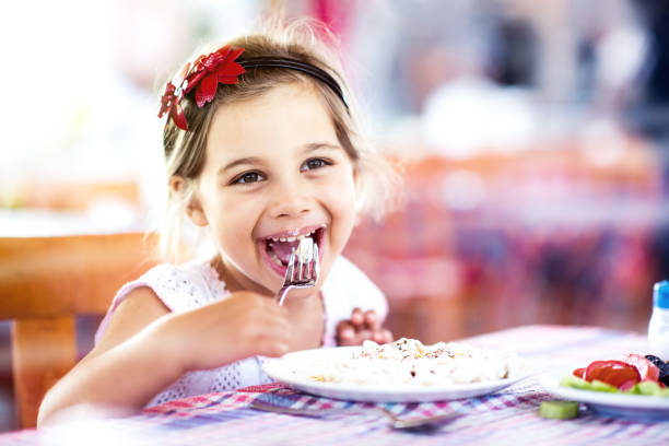 Little Girl Having Her Meal With Pleasure stock photo