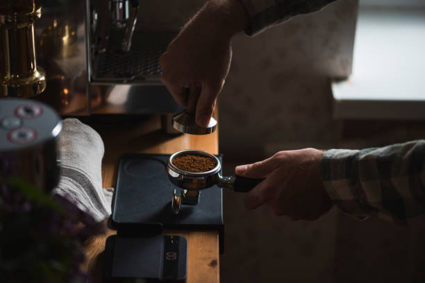 istock The process of making coffee step by step. Man tamping freshly ground coffee beans in a portafilter on a working wooden table 699931082