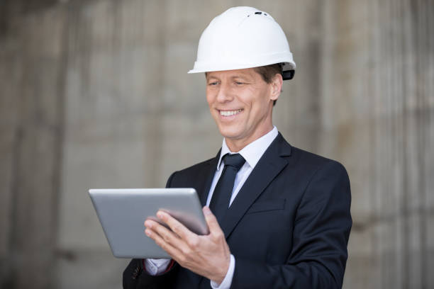 istock Smiling middle aged businessman in hard hat using digital tablet 699931190