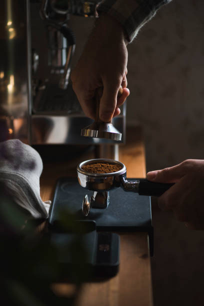 단계적으로 커피를 만드는 과정. 남자 갓 충전 작업 나무 테이블에 portafilter에 커피 콩 지상 - tamping 뉴스 사진 이미지