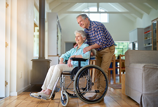 Shot of a happy senior woman in a wheelchair relaxing with her husband at home