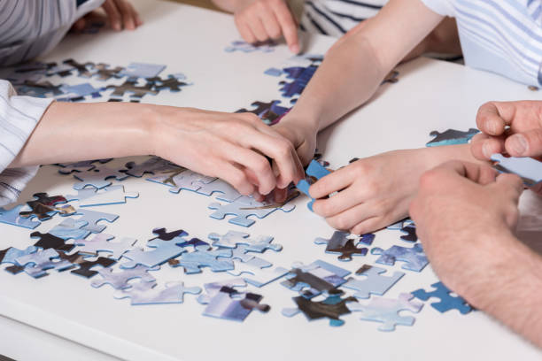 istock Cropped image family playing with puzzle on table at home together 699954260