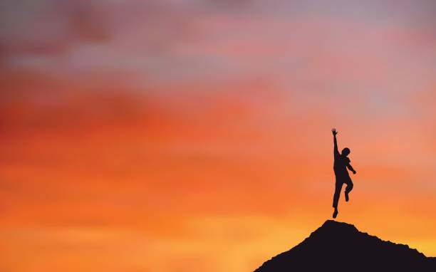 istock Silhouette of happy man jumping on Mountain cliff looking at sunset sky background 699961326
