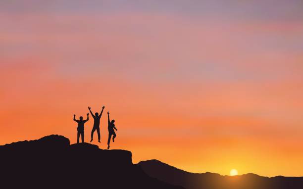 istock Silhouette of happy men jumping on Mountain cliff looking at sunrise sky background 699961392