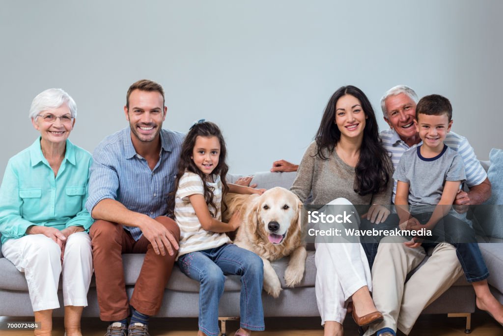 Family sitting on sofa with dog Family sitting on sofa with dog in living room Dog Stock Photo