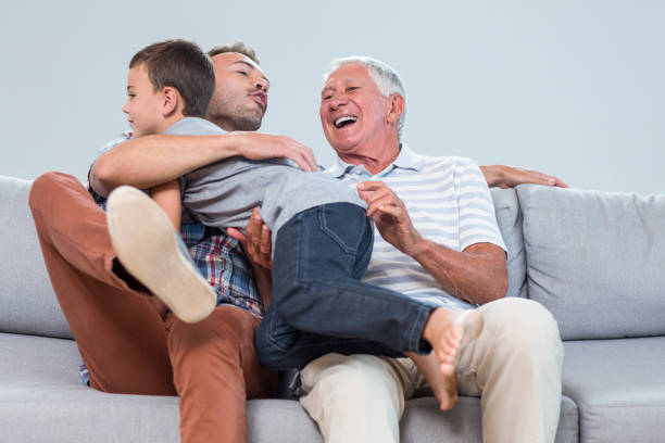 Teenage boy helping his grandfather to assemble shelf at home showing positive emotion