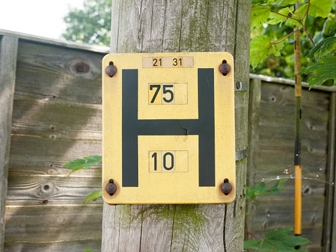a yellow h sign outside on a wooden post in the street