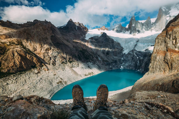Tracking boots shoes on a blue lake background among mountains and cloudy sky Tracking boots shoes on a blue lake background among mountains and cloudy sky patagonia chile photos stock pictures, royalty-free photos & images