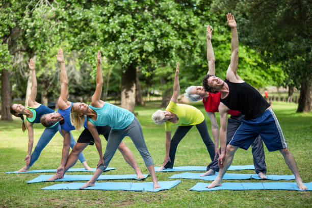 fitness-klasse stretching - yoga exercising outdoors group of people stock-fotos und bilder