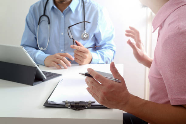 medical doctor using mobile phone and consulting businessman patient having exam as hospital professionalism concept - telephone doctor medical exam healthcare and medicine imagens e fotografias de stock