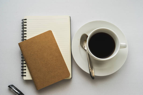istock Coffee in white cup with Journal book and pencil 700164514