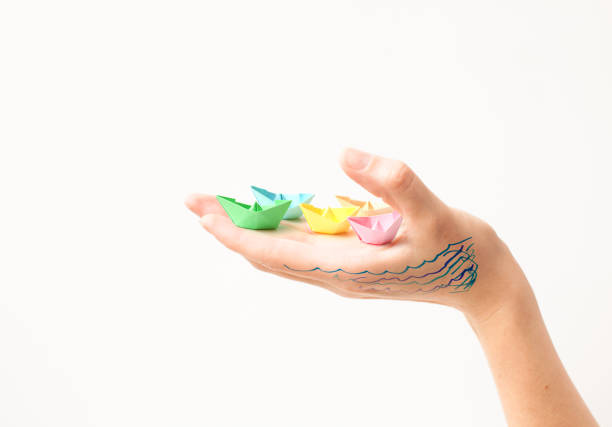 istock Paper colored boats on a hand on white 700168452