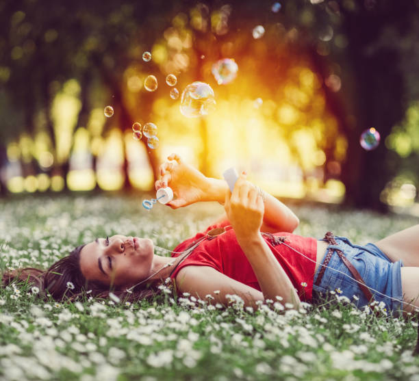 istock Relaxed woman blowing soap bubbles in the park 700171470