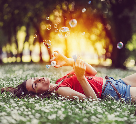 Girl listening to the music and blowing soap bubbles