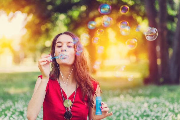 istock Young woman blowing soap bubbles in the park 700171770