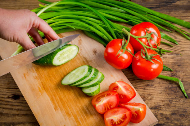 istock Slicing cucumber on wooden cutting board 700171944