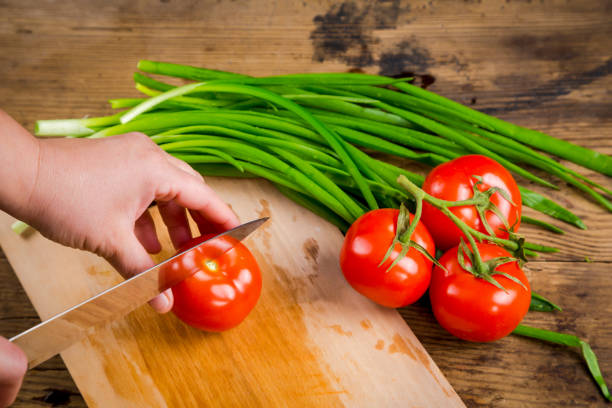 istock Cut tomato on wooden cutting board, above view 700180288
