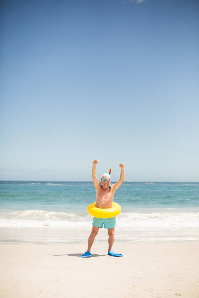 istock Senior man with swimming ring and flippers at the beach 700184232