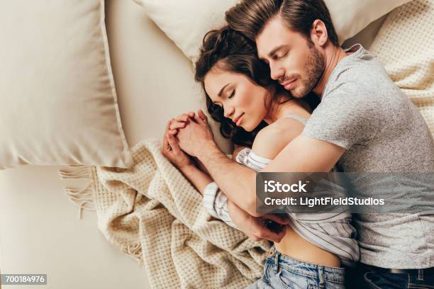 Top View Of Beautiful Happy Young Couple Hugging While Sleeping On Bed Stock Photo - Download Image Now