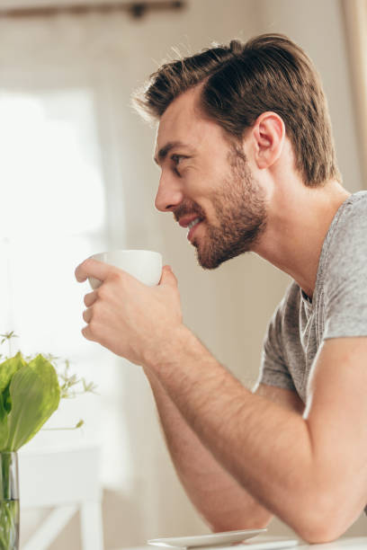 istock young handsome man smiling and drinking coffee at home 700190948