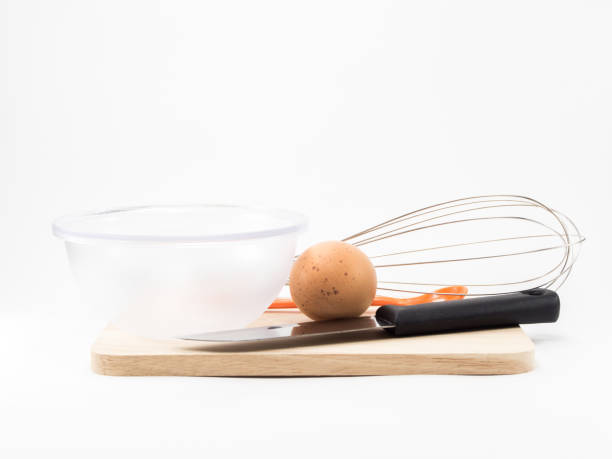 istock eggs in cup and whisk knife on wood square isolated on white background 700193340