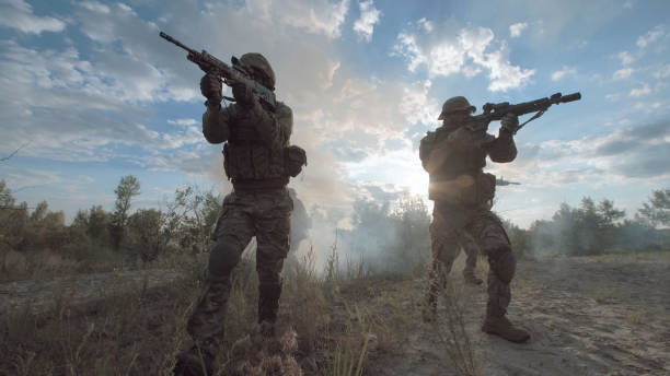 military forces walking on battlefield - guerra imagens e fotografias de stock