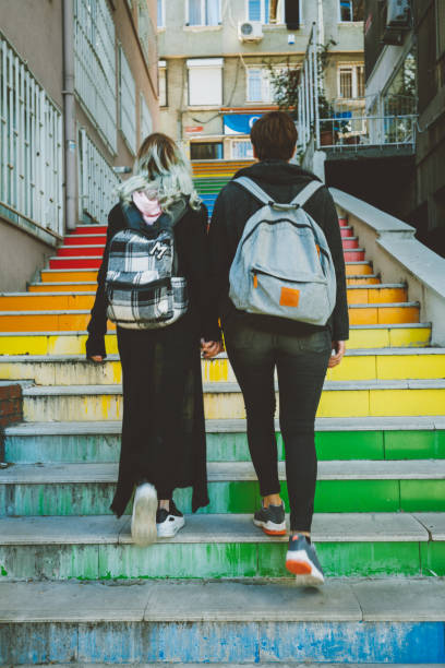 Urban lesbian couple walking on street Same sex young female real couple hanging out and walk hand in hand on a colorful stairs in Istanbul, Turkey on sunny day gay long hair stock pictures, royalty-free photos & images