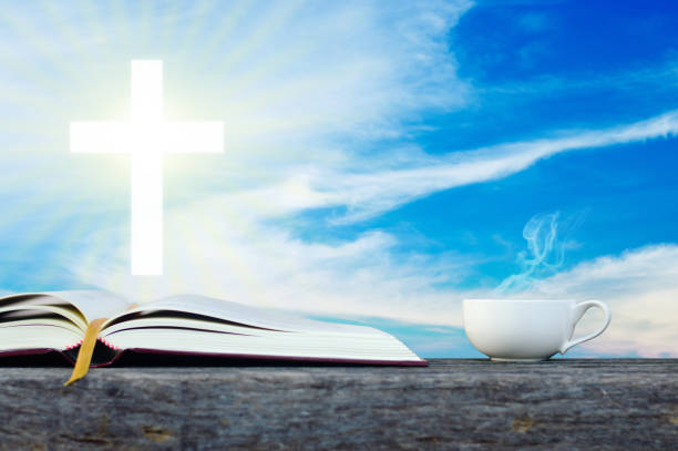 istock Open holy bible with white cross in the blue sky back ground. 700195316