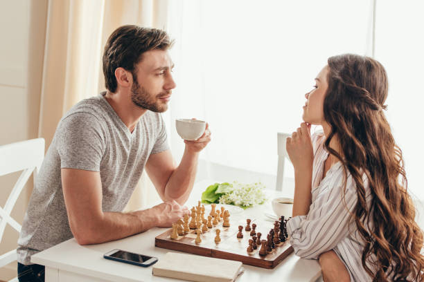 istock young couple playing chess and talking while drinking coffee at home 700203146