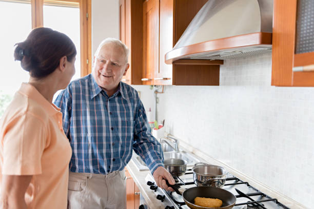 istock Female caregiver and senior man in kitchen 700208314