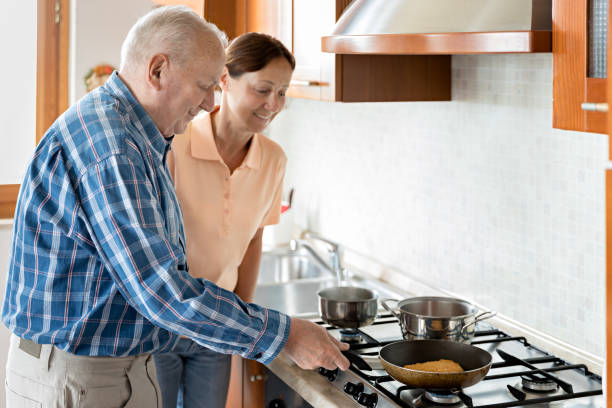 istock Female caregiver and senior man in kitchen 700208512