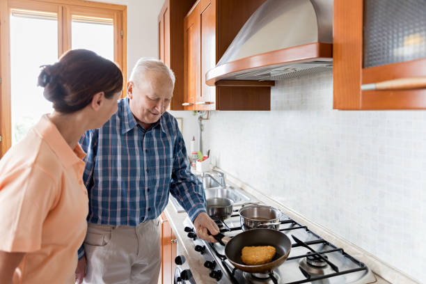 istock Female caregiver and senior man in kitchen 700209348