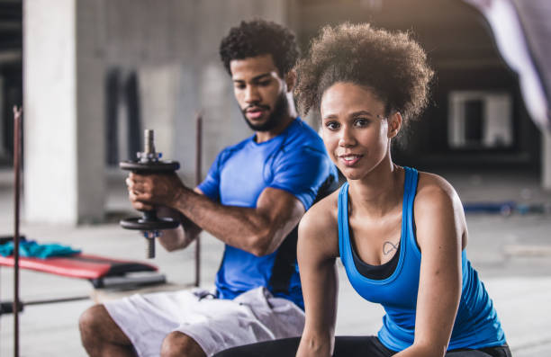 istock Young Woman Lifting Weights With Personal Coach Beside Her 700215866