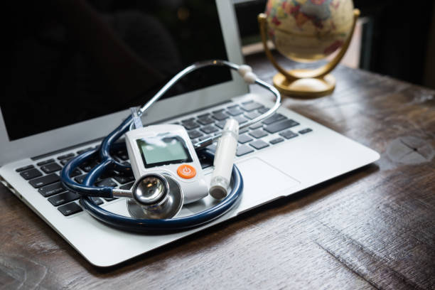 Technology and medicine - Silver stethoscope and blood glucose meter over laptop keyboard. Concept of healthcare medical and check up, diabetes, glycemia. stock photo
