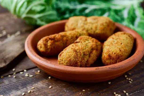 closeup of an earthenware plate with some homemade croquetas, spanish croquettes, on a rustic wooden table