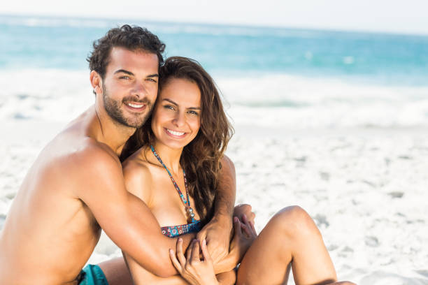 istock Happy couple sitting on the beach 700238526