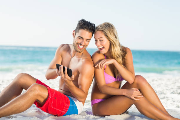 istock Happy couple sitting back to back on beach 700241060