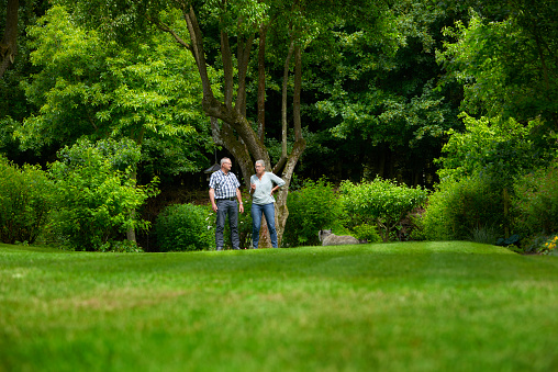 Retired couple in their park-like garden. Healthy and happy couple enjoying their life with a fantastic well kept garden. Having gardening as a passion and theraphy. 5000 sqm garden. Active life in the garden keeps the people sound and healthy and gives common interests.