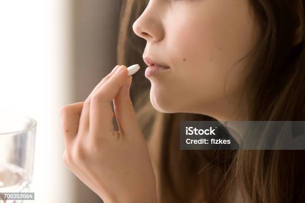 Close Up Image Of Woman Drinking Round White Pill Stock Photo - Download Image Now - Pill, Medicine, Women