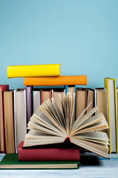 istock Book stacking. Open book, hardback books on wooden table and blue background. Back to school. Copy space for text 700267936