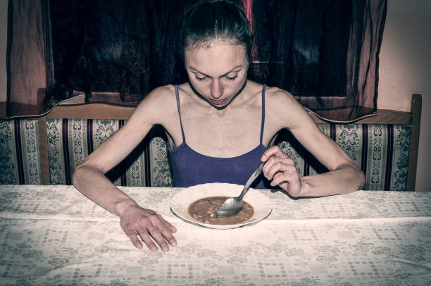 Anorexia. Skinny anorexic girl holding a spoon and look at the plate with food. Anorexia. Skinny anorexic girl holding a spoon and look at the plate with food. anorexia nervosa stock pictures, royalty-free photos & images