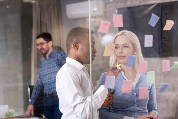 istock Business team discussing ideas on glass wall with sticky notes 700282232