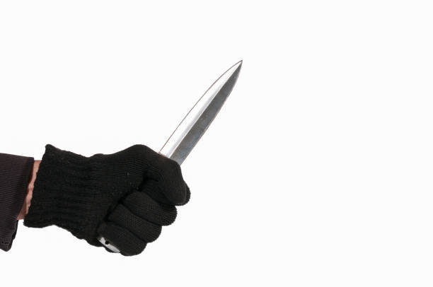 istock Robber. Hand with black glove holding a dagger knife. Isolated on a white background. 700290002